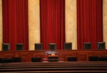 Congress Takes Aim at War Powers Empty courtroom bench with red curtains and leather chairs