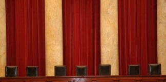 Empty courtroom bench with red curtains and leather chairs