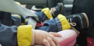baby hand resting on a pink car seat