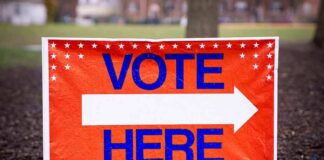 Vote here sign with right-pointing arrow outdoors