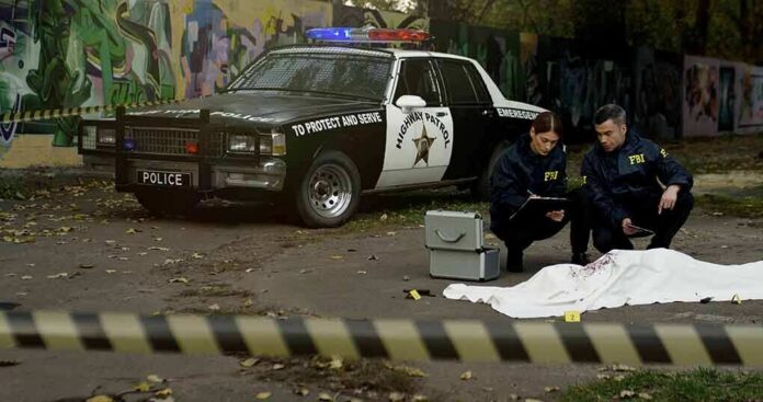 Crime scene with police car and two investigators by a covered body