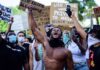 America’s Lynching History Still Shapes Today Shirtless protester raises fist while crowd holds signs