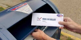 Person mailing a ballot into a blue street mailbox