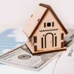 Teardown Twist Engulfs LA Power Player Wooden house model on money and contract papers