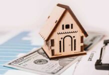 Wooden house model on money and contract papers