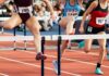 Female athletes clearing hurdles on a track