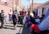 Police officers interact with people in an alley encampment