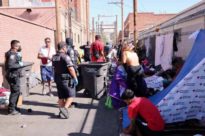 shutterstock_2307142885-6 Police officers interact with people in an alley encampment