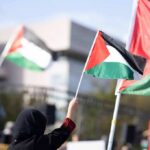 Trump’s Gaza Plan Tests Arab American Support Person waving a Palestinian flag at a rally