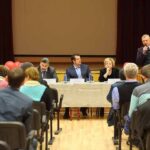 CMS Boss Lands Role at MAHA Summit Panel of speakers at a community meeting addressing an audience