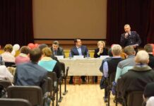 Panel of speakers at a community meeting addressing an audience