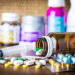 Psychedelics Enter VA? Legion Drops Bomb Medicine pills and syringe on table with brown bottle