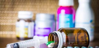 Medicine pills and syringe on table with brown bottle