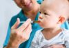 Baby taking liquid medicine from an oral syringe held by an adult