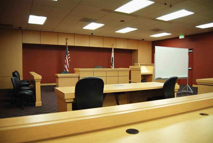 Interior view of an empty courtroom with wooden furniture and American flags