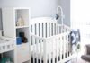 White baby crib with mobile in a bright nursery