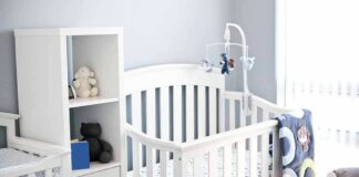 White baby crib with mobile in a bright nursery