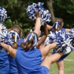 cheerleaders performing with blue and white pom-poms