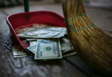 Inside a $1.6 Billion Venezuelan Money Trail Broom sweeping dollar bills into red dustpan floor
