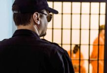 Security guard watching inmates behind jail bars