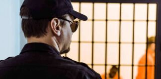 Security guard watching inmates behind jail bars