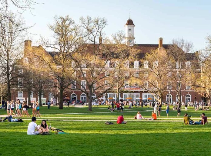 Students relaxing on a campus quad in front of a brick academic building