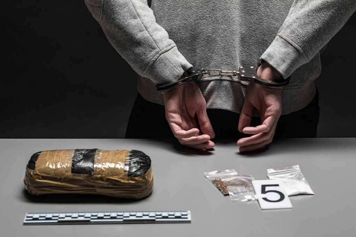 person in handcuffs behind back over table with seized packages