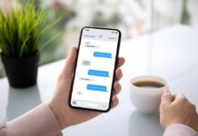 Person holding smartphone with messaging app beside a cup of coffee