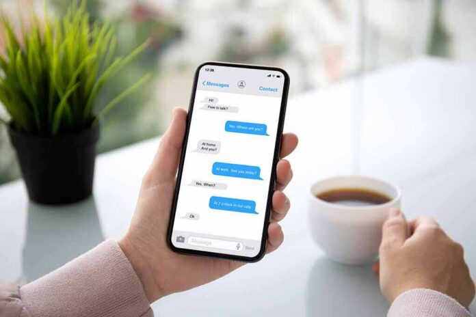 Person holding smartphone with messaging app beside a cup of coffee