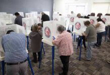 Voters fill out ballots at polling booths in a busy voting room