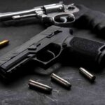 Handgun and revolver with scattered bullets on dark surface