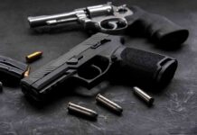 Handgun and revolver with scattered bullets on dark surface