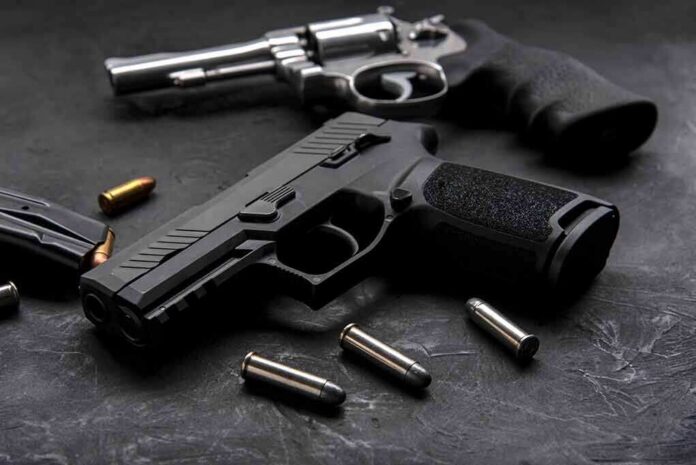 shutterstock_1454438033 Handgun and revolver with scattered bullets on dark surface