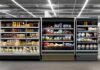 Supermarket refrigerated display cases with drinks, produce, and prepared foods