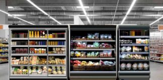 Supermarket refrigerated display cases with drinks, produce, and prepared foods