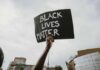 Protester holds a handwritten sign aloft at a rally