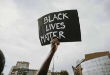 Protester holds a handwritten sign aloft at a rally