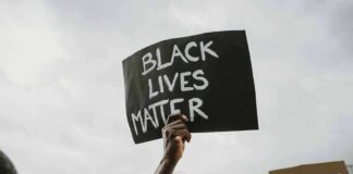 Protester holds a handwritten sign aloft at a rally