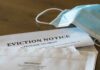 Eviction notice and torn envelope beside blue surgical masks