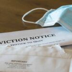 Eviction notice and torn envelope beside blue surgical masks