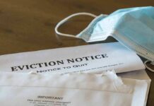 Eviction notice and torn envelope beside blue surgical masks