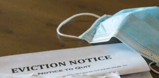 Eviction notice and torn envelope beside blue surgical masks