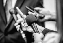Chilling Ultimatum Over Dessert – Douglas Rattled Microphones and recorders held toward a speaker