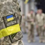 Sealed Evidence, Open Diplomacy – What’s Hiding? Soldier in camouflage with Ukrainian flag patch and yellow armband