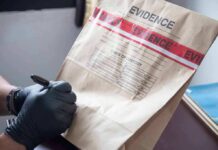 Gloved hands labeling a sealed evidence bag