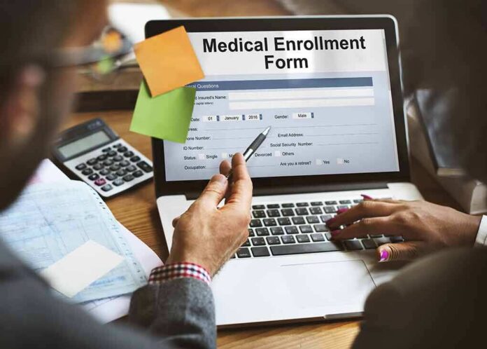 Laptop displaying a medical enrollment form with two people reviewing it