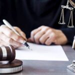 FBI Probes Bombshell AG Email Judge writing at desk with gavel and Lady Justice statue