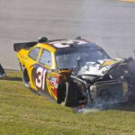 Race car with heavy front-end damage on grass
