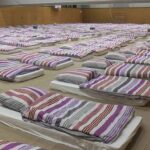 400,000 Homes Short: Dutch Housing Tensions Persist rows of mattresses with striped bedding in a large hall