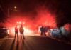 Firefighters and police at a nighttime car fire scene